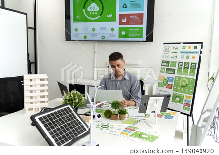 Caucasian adult man environmental consultant analyzing green business strategies corporate sustainability reports renewable energy solutions data office workspace Caucasian adult man environmental consultant analyzing green business strategies corporate sustainability reports renewable energy solutions data office workspace 139040920