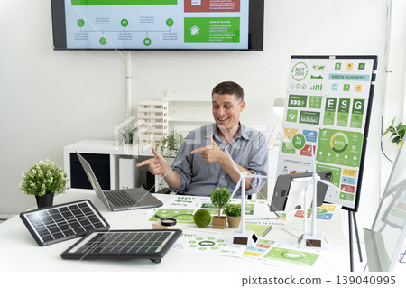 Adult Caucasian man discusses green business strategies sustainable energy solutions modern office showing ESG reports renewable technology consultant explaining eco friendly concepts corporate 139040995
