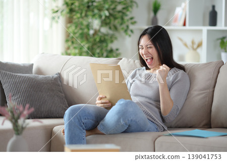 Excited asian woman checking paper documents Excited asian woman checking paper documents 139041753