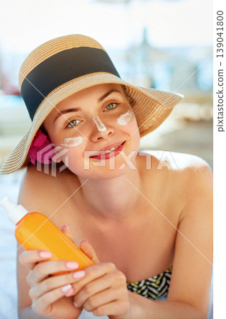 Skincare. Beauty Concept. Young pretty woman holding sun cream and applying on her face. Female in hat smear sunscreen lotion on skin and touch own face. Skin Protection and dermatology. Skincare. Beauty Concept. Young pretty woman holding sun cream and applying on her face. Female in hat smear sunscreen lotion on skin and touch own face. Skin Protection and dermatology. 139041800