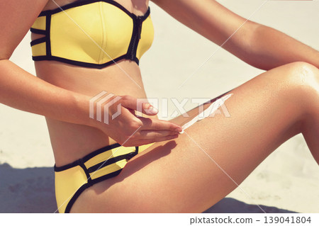 Closeup on female hand applying sun screen creme on leg. Skincare. Sun protection sun cream, on her smooth tanned legs. Closeup on female hand applying sun screen creme on leg. Skincare. Sun protection sun cream, on her smooth tanned legs. 139041804