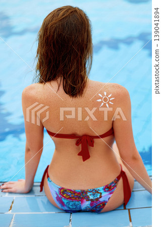 Woman With Suntan Lotion At The Beach In Form Of The Sun. Portrait Of Female With the Drawn Sun On a Shoulder On The Pool 139041894