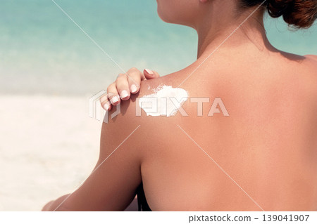 Woman applying sunscreen creme on tanned shoulder. Skincare. Body Sun protection suncream. Bikini hat woman applying moisturizing sunscreen lotion on back. Woman applying sunscreen creme on tanned shoulder. Skincare. Body Sun protection suncream. Bikini hat woman applying moisturizing sunscreen lotion on back. 139041907
