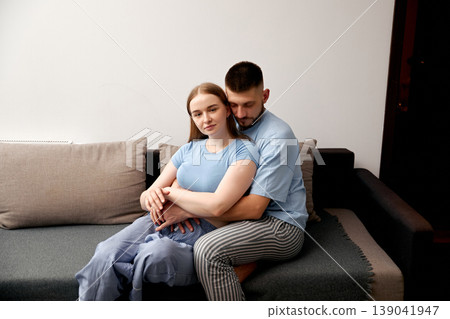 Couple sitting on a couch together at home during afternoon hours 139041947
