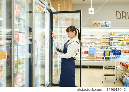 一位女店員正在檢查冰箱裡的物品。 139042042