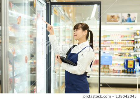 一位女店員正在檢查冰箱裡的物品。 一位女店員正在檢查冰箱裡的物品。 139042045