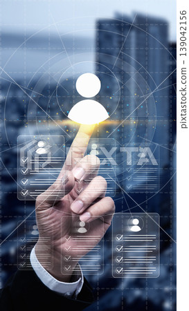 Businessman hand touching virtual profile icons on a digital interface, representing recruitment, human resources management, and talent acquisition in a modern city Businessman hand touching virtual profile icons on a digital interface, representing recruitment, human resources management, and talent acquisition in a modern city 139042156