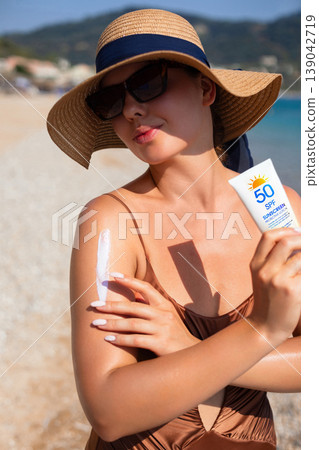 Beauty Woman Holding Sunscreen And Applying Sunblock On Shoulder At Beach. Skincare And Sun Protection Concept. Female Using Lotion For Healthy Skin Beauty Woman Holding Sunscreen And Applying Sunblock On Shoulder At Beach. Skincare And Sun Protection Concept. Female Using Lotion For Healthy Skin 139042719