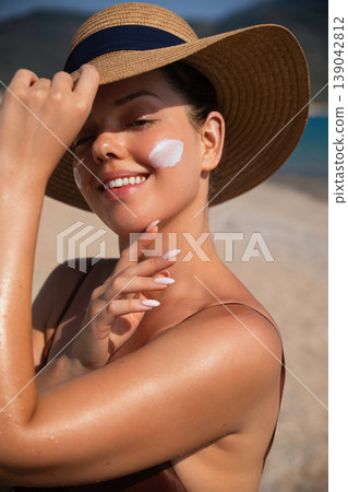 Pretty Woman Smiling And Touching Face With Sunscreen At Beach. Beauty Skincare Concept. Female Using Sun Cream Lotion Pretty Woman Smiling And Touching Face With Sunscreen At Beach. Beauty Skincare Concept. Female Using Sun Cream Lotion 139042812