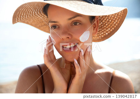 Beauty Woman Smiling And Touching Face At Beach With Sunscreen. Skincare And Sun Protection Concept. Female Using Sun Cream Lotion 139042817