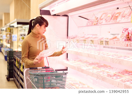 一位女士在超市肉品區購物。 一位女士在超市肉品區購物。 139042955