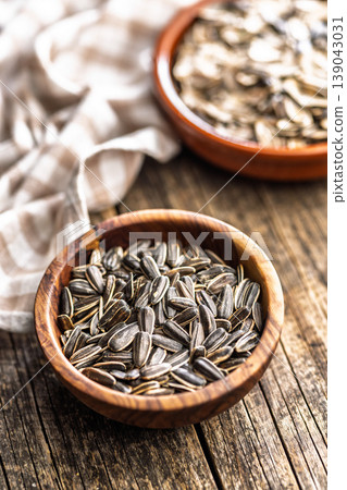 Close-Up Sunflower Seeds In A Wooden Bowl On Rustic Wood Table With Linen Cloth 139043031