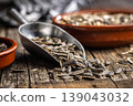 Sunflower Seeds in Metal Scoop on Rustic Wooden Table With Ceramic Bowls for Snacking and Cooking 139043032