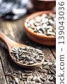 Close-Up of Sunflower Seeds in Wooden Spoon With Rustic Bowl on Weathered Table 139043036