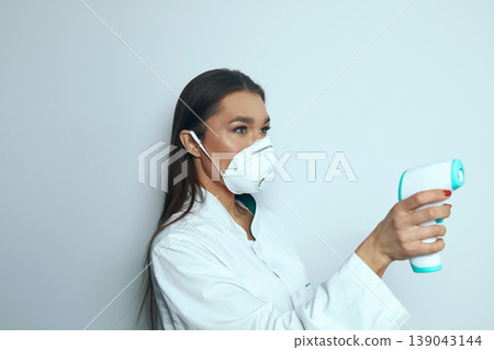 Health worker uses thermometer to check temperature in medical setting during health screening process 139043144