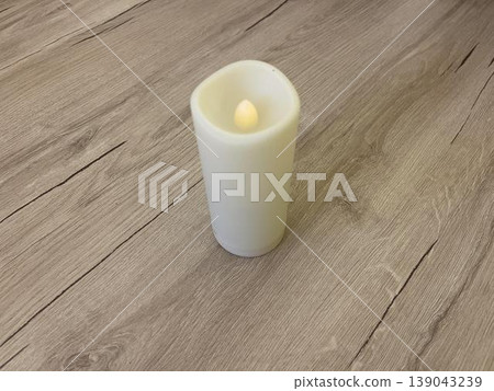 a white candle on a wooden floor a white candle on a wooden floor 139043239