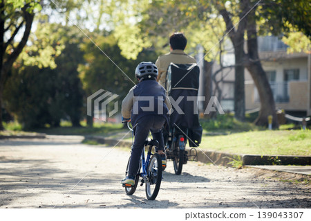 A child and their father riding bicycles in a park in spring. 139043307
