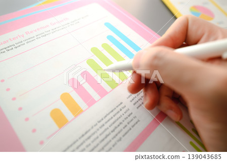 A hand pointing at a graph and a report A hand pointing at a graph and a report 139043685