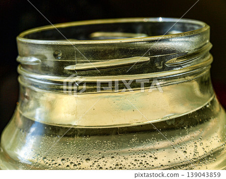 Dramatic low key macro of a glass jar thread with water bubbles. Caravaggiesque lighting creates high contrast, highlighting air spheres and optical refraction against a deep dark background. Dramatic low key macro of a glass jar thread with water bubbles. Caravaggiesque lighting creates high contrast, highlighting air spheres and optical refraction against a deep dark background. 139043859