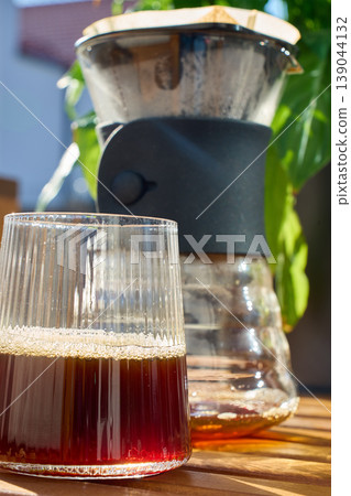 Glass of fresh brewed coffee with dripper carafe in sunlight Glass of fresh brewed coffee with dripper carafe in sunlight 139044132