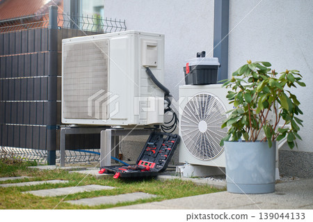 Outdoor heat pump units with tools during residential service Outdoor heat pump units with tools during residential service 139044133