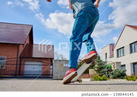 Skateboarder doing trick on skateboard on residential street Skateboarder doing trick on skateboard on residential street 139044145
