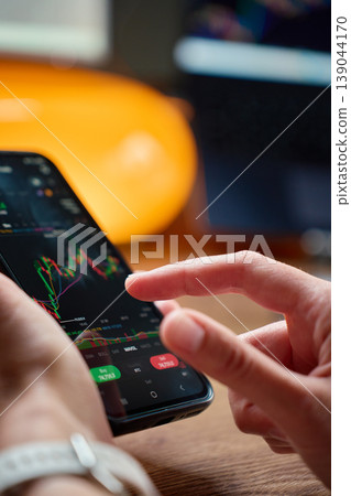 Person analyzing stock market chart on smartphone at desk 139044170