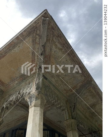 Architectural detail of ornate ancient column and ceiling with cloudy sky background 139044232