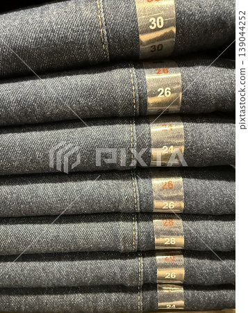 Folded denim jeans in various sizes on display in retail store as clothing background Folded denim jeans in various sizes on display in retail store as clothing background 139044252