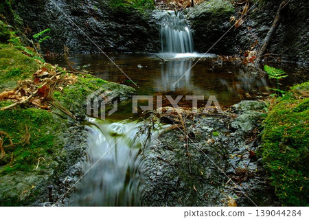 A clear stream and small waterfall nourish the forest; a refreshing landscape flowing through moss-covered rocks. A clear stream and small waterfall nourish the forest; a refreshing landscape flowing through moss-covered rocks. 139044284