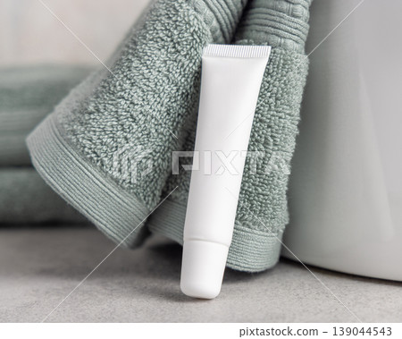 White blank eye cream tube mockup near light green bath towel. Cosmetic skincare product packaging White blank eye cream tube mockup near light green bath towel. Cosmetic skincare product packaging 139044543