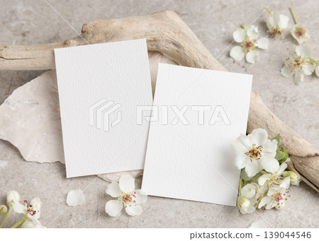 Blank cards mockup with white spring flowers and driftwood on beige stone. Wedding invitation Blank cards mockup with white spring flowers and driftwood on beige stone. Wedding invitation 139044546