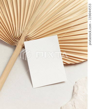 Blank portrait card mockup with dried palm leaf on beige stone top view, boho wedding stationery Blank portrait card mockup with dried palm leaf on beige stone top view, boho wedding stationery 139044553