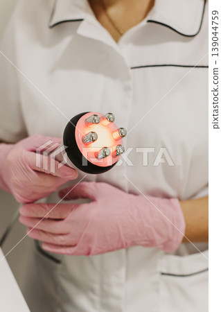 Cosmetologist in pink glove holds an RF lifting device at cosmetology clinic. Close up. Cosmetology concept. 139044759