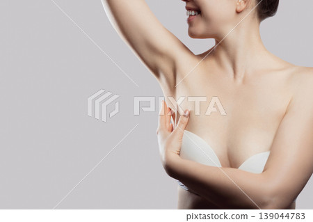 Skin care. Armpit epilation, laser hair removal. Young woman holding her arms up and showing clean underarms, 139044783