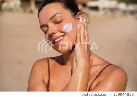 Beauty Woman Touching Face With Sunscreen On Skin At Beach. Skincare And Sun Protection Concept. Female Using Sun Cream Lotion Beauty Woman Touching Face With Sunscreen On Skin At Beach. Skincare And Sun Protection Concept. Female Using Sun Cream Lotion 139044830