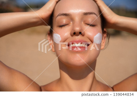 Pretty Woman With Sunscreen On Face And Hands On Head At Beach. Beauty Skincare Concept. Female Using Sun Cream Lotion 139044834
