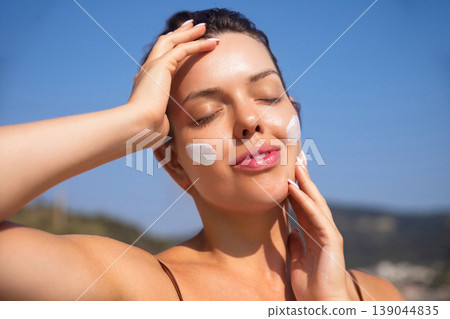 Beautiful Woman Touching Face And Smiling With Sunscreen At Beach. Beauty Skincare And Sun Protection Concept 139044835