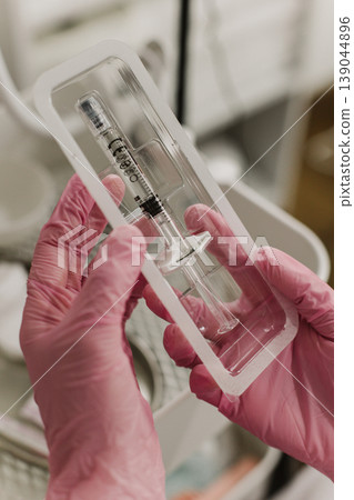 Cosmetologist wearing pink glove and holding a syringe for procedure at cosmetology clinic. Close up. Cosmetology concept. Cosmetologist wearing pink glove and holding a syringe for procedure at cosmetology clinic. Close up. Cosmetology concept. 139044896