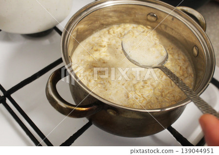 Cook cooking porridge on gas stove top view Cook cooking porridge on gas stove top view 139044951