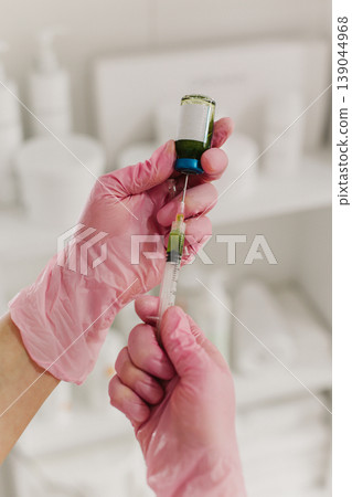 Cosmetologist wearing pink glove and filling syringe at cosmetology clinic. Close up. Cosmetology concept. 139044968