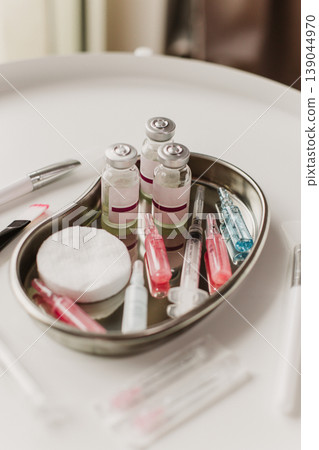 A metal tray with cosmetic instruments and ampoules for cosmetic procedure on a white background. Cosmetology concept. A metal tray with cosmetic instruments and ampoules for cosmetic procedure on a white background. Cosmetology concept. 139044970
