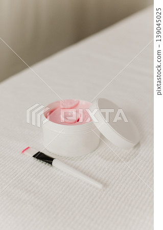 Facial pink clay mask in white jar and brush on a white background. Skin care beauty product. Cosmetology concept. Facial pink clay mask in white jar and brush on a white background. Skin care beauty product. Cosmetology concept. 139045025