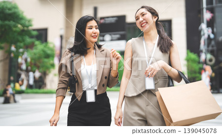 Two business women holding shopping bag happy spending salary money together Two business women holding shopping bag happy spending salary money together 139045078