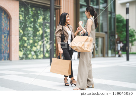 Full body two business women holding shopping bag happy spending salary money together Full body two business women holding shopping bag happy spending salary money together 139045080