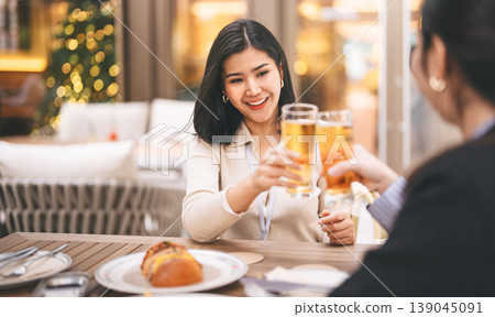 Two young adult asian business women enjoy eating dinner cheers beer together on night at restaurant Two young adult asian business women enjoy eating dinner cheers beer together on night at restaurant 139045091