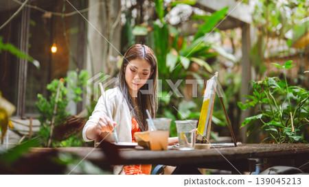 Portrait of happy young adult asian woman painting brush on canvas at workshop art lesson class. Portrait of happy young adult asian woman painting brush on canvas at workshop art lesson class. 139045213