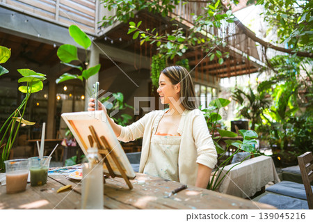 Gen Z Influencer content creator woman using smartphone with creativity painting at workshop cafe 139045216