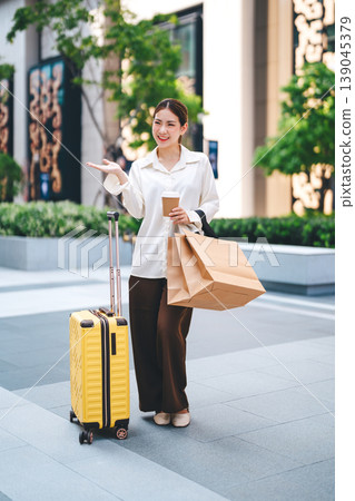 Young adult business asian woman happy walking with travel luggage and shopping bags 139045379