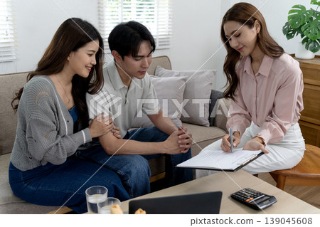Asian consultant meets young adult couple home discussing paperwork financial planning real estate insurance advice contract signing loan agreement 139045608